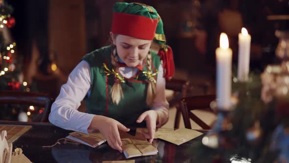 Happy female elf holding a stack of envelopes.