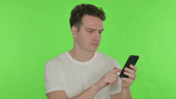 Young Man Celebrating on Smartphone on Green Background