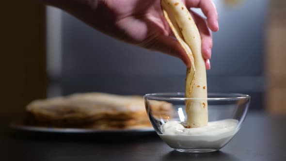 girl dunks pancake in sour cream