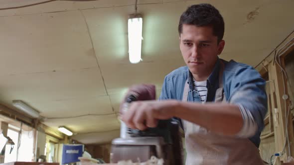 Young Carpenter Smoothing Wood with Grinder alt