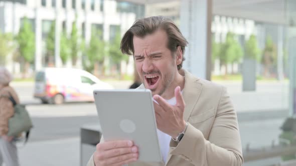 Upset Young Man Reacting to Loss on Tablet Outdoor