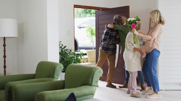 Two diverse senior couples hugging and greeting each other at home