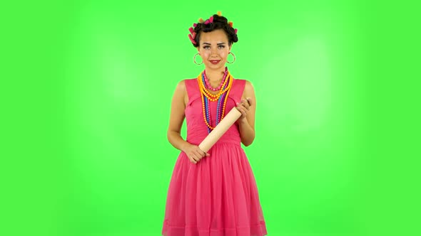 Girl with a Rolling Pin in Her Hands Seductively Looks at the Camera. Green Screen