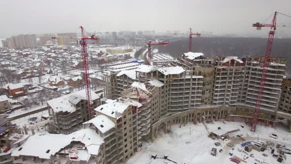 Flying over suburbs of winter city and construction site of apartment complex