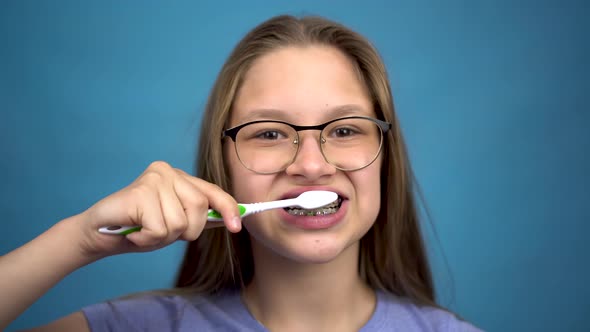 Girl with Braces Brush Her Teeth with a Toothbrush Closeup. A Girl with Colored Braces on Her Teeth