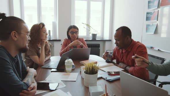 Mixed-Aged Multiethnic Colleagues Working at Meeting Table in Office