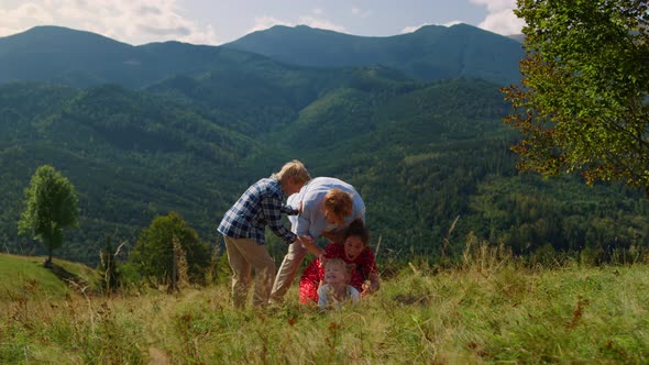Family Falling Grass Playing on Mountain Hill