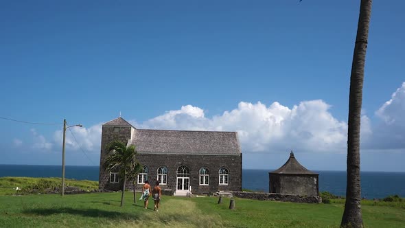 Two young girls walking towards a stone church on St. Kitts and Nevis,Caribbean.