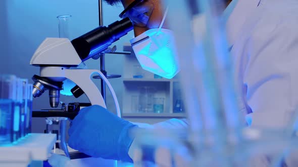 Asian scientist doing some research and looking through a microscope in laboratory.