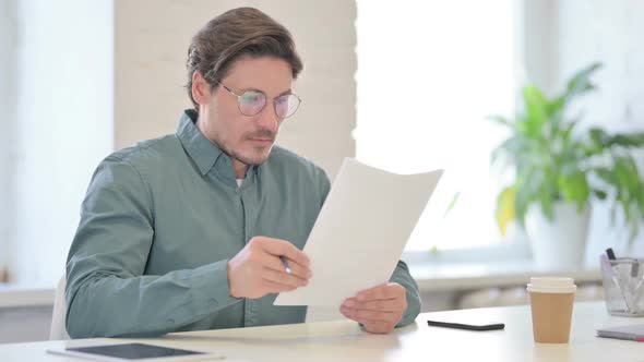Middle Aged Man Reading Documents in Office