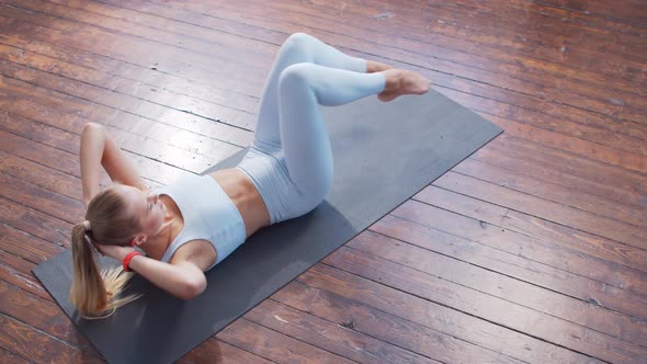 Young and sporty girl in sportswear is doing exercises at home.