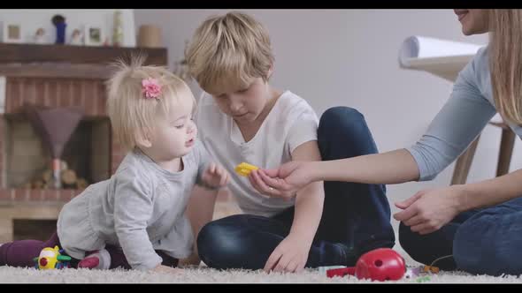 Portrait of Happy Caucasian Family Resting Indoors. Mother Giving Toy To Her Baby Daughter