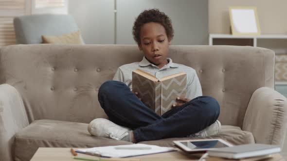 African Boy Reading Book on Couch