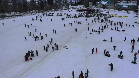 Aerial Slow Moving Shot of a Crowd Enjoying Themself in Snow Adventure Valley in Solang , Himachal