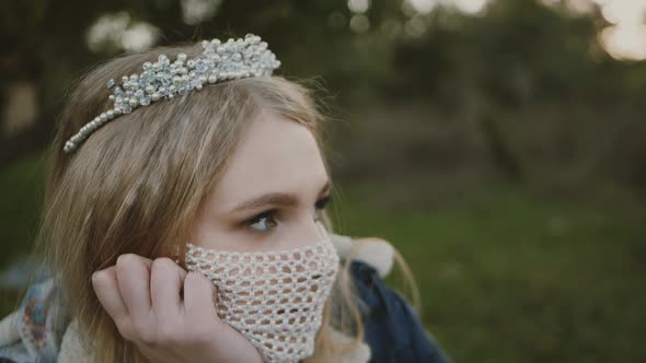 portrait of the bride in a mask posing. Beautiful young bride in a wedding dress in the park. She ha