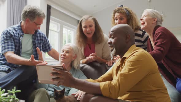 Animation of happy diverse female and male senior friends using tablet at home