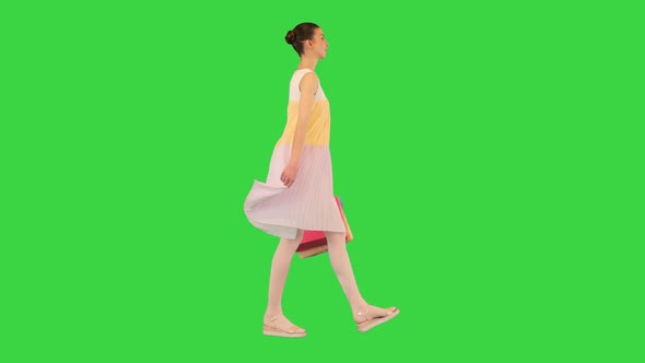 Teenager Girl in a Summer Dress Walking with Shopping Bags on a Green Screen Chroma Key