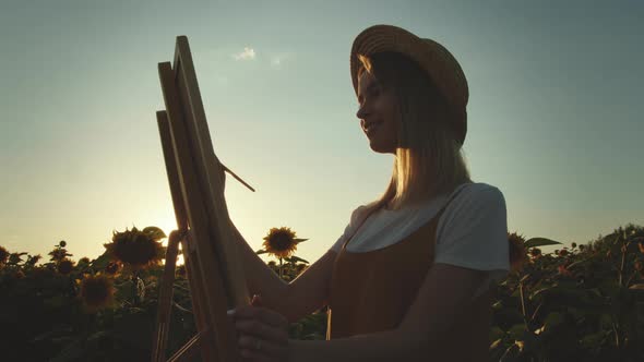 A Woman is Drawing with a Brush on Canvas