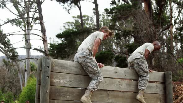 Military people climbing hurdles during obstacle course 4k