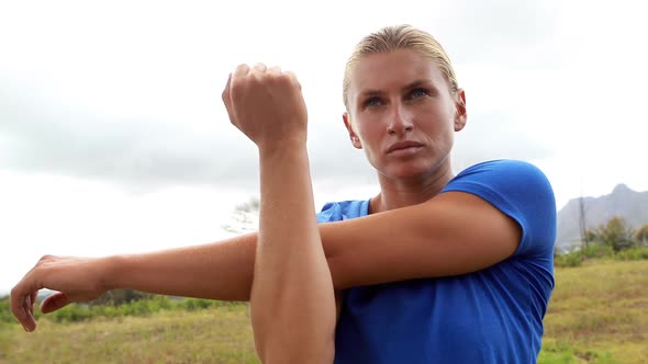 Fit woman performing stretching exercising during obstacle course