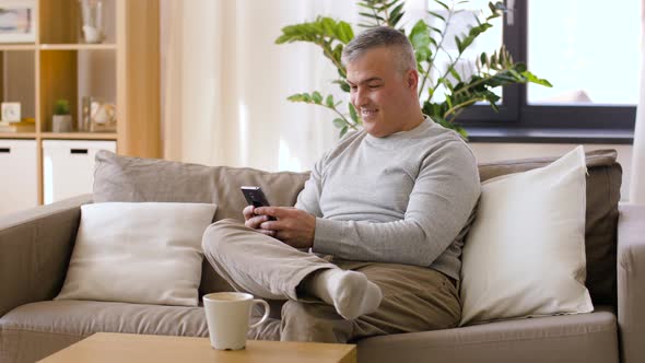 Man with Smartphone Drinking Coffee at Home 11