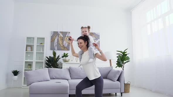 Woman Doing Sit-Ups with Her Cute Funny Little Daughter which Sitting on Her Neck at Home