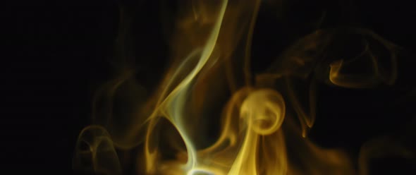 Golden incense flames swirling on black background alt