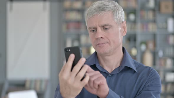 Portrait of Middle Aged Man Celebrating on Smartphone with Fist