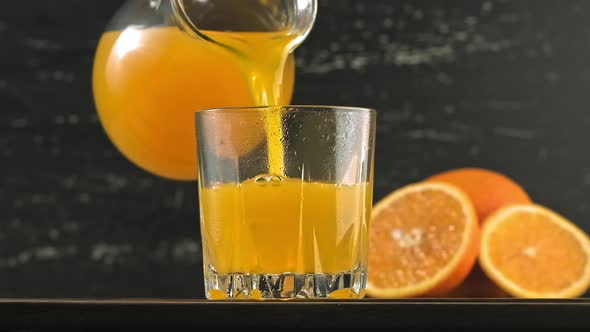 Pouring Orange Juice Into Glass with Ice Cubes. Yellow Lemonade Pouring in Glass
