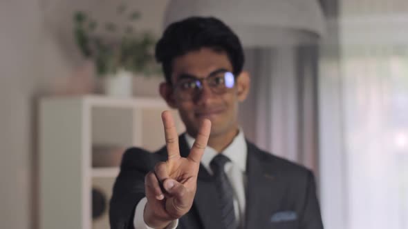 Young man, formal wear. shows victory sign by hand. Peace expression