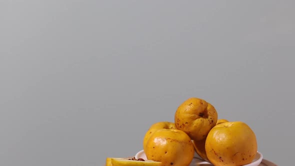 Quince Fruits On A Plate. Fruit Is Yellow. The Plate Rotates On The Stage.