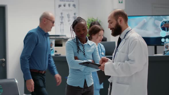 African American Woman and Doctor Analyzing Diagnosis on Digital Tablet