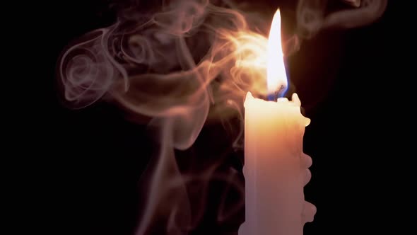 White Candle Burns in a Cloud of Smoke on Black Background