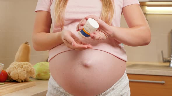 CLoseup of Pregnant Woman Pouring Vitamin Pills on Hand From Plastic Bottle Container