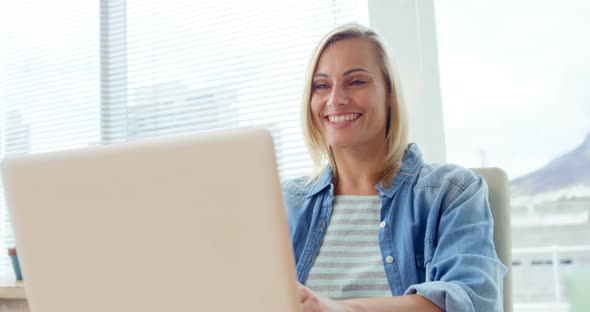 Businesswoman closing laptop at her desk