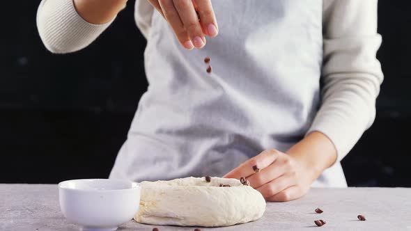 Woman adding chocolate chips into the dough