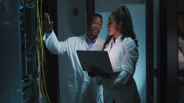 African american computer technicians using laptop working in business server room