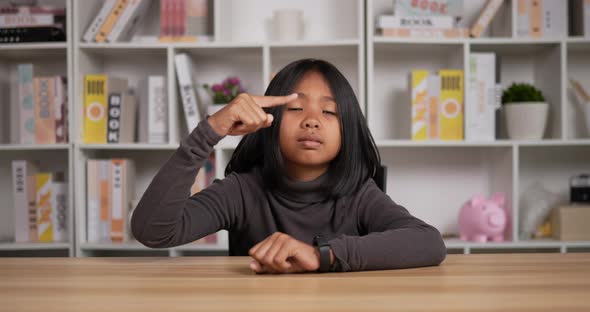 Girl sitting at desk and pointing on watch