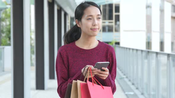 Shopping woman holding paper and using mobile phone 