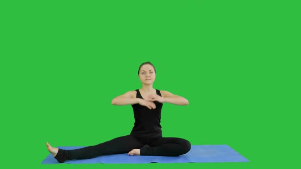 Young Woman Stretching Her Legs While Doing Yoga Practice on a Green Screen, Chroma Key