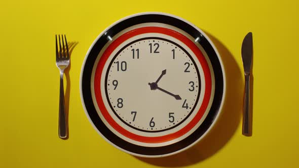 Timelapse clock on the plate on the table with the cutlery