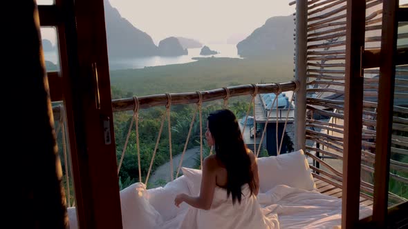 Woman Mid Age on Vacation in Thailand Waking Up in the Jungle with Bedroom Outside Watching Sunrise