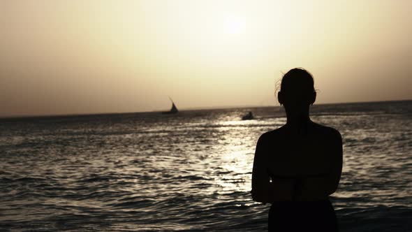 Silhouette of a Beautiful Young Woman Looking at the Sunset in the Ocean Africa