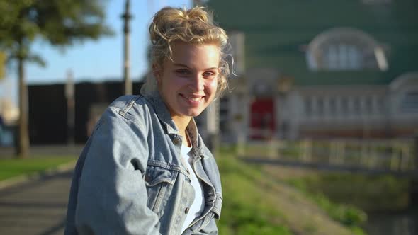 Slowmotion of Tender Beautiful Blond European Girl in Denim Jacket Leaning on Fence Turning at