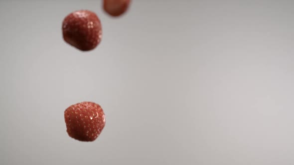 Whole and half sliced strawberries flying through in front of the camera