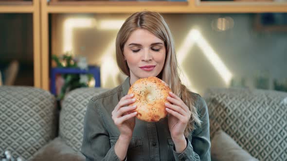 Portrait of Smiling Young Girl Biting Appetizing Baking Bun