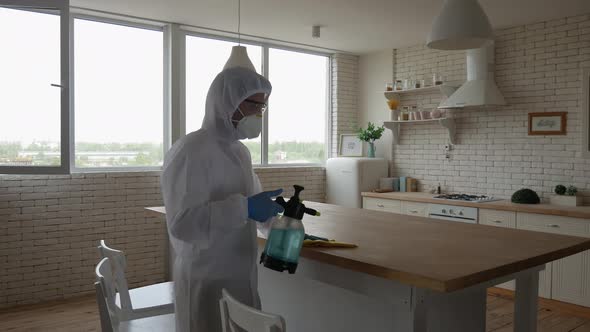 Disinfection at home. A man in a protective suit cleans the table with a chemical