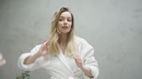 Goodlooking Woman in Bathrobe Looking at Mirror in the Morning