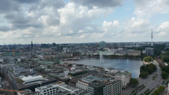 Sliding Aerial Footage of Water Surface Surrounded By Buildings and with Fountain in Middle