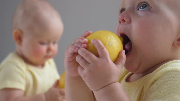 Cute Funny Twin Baby Girls Playing with Lemons.